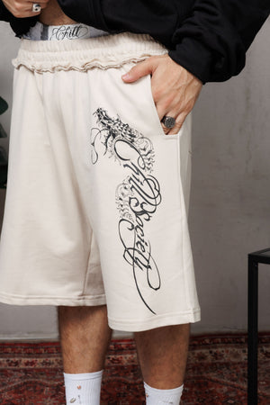 Baggy Jort CHILL BEIGE unisex 300gr — algodón burda con estampado calligráfico gótico en pierna y efecto tela sobrante en pretina, streetwear hecho en Colombia