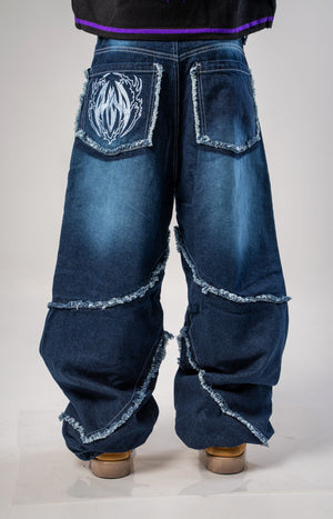 Jeans baggy CHILL azul washed — denim con bordes deshilachados curvos y bordado tribal, streetwear hecho en Colombia