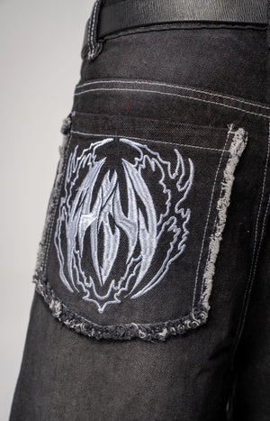Jeans baggy CHILL negro washed — denim con bordes deshilachados curvos y bordado tribal, streetwear hecho en Colombia