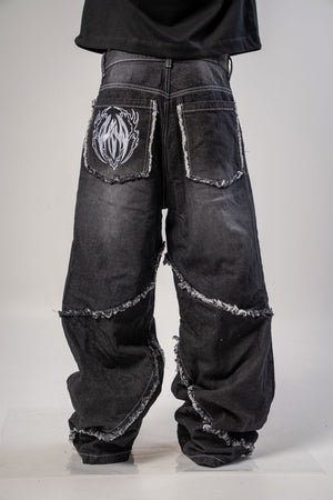 Jeans baggy CHILL negro washed — denim con bordes deshilachados curvos y bordado tribal, streetwear hecho en Colombia