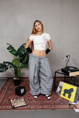 Top off shoulder Bellakita CHILL blanco cropped — algodón spandex con manga asimétrica y lettering script en serigrafía roja, top femenino streetwear hecho en Colombia